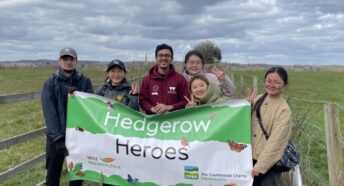 People holding a banner in the countryside with 'Hedgerow Heroes' written on it