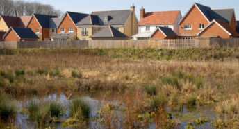 WAterlogged ground on a floodplain near new houses on a housing development in Suffolk, England
