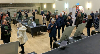 Large groups of people reading display boards and talking with exhibitors at the Getting Solar OFF the Land exhibition