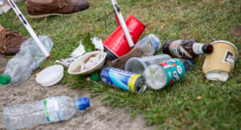 Close-up of a grabber being used to pick up discarded litter from a grassed area.