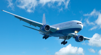 Image of an airplane in flght against a blue sky with wispy clouds