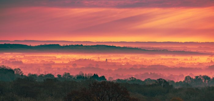 A misty sunrise scene in Tonbridge over trees and fields